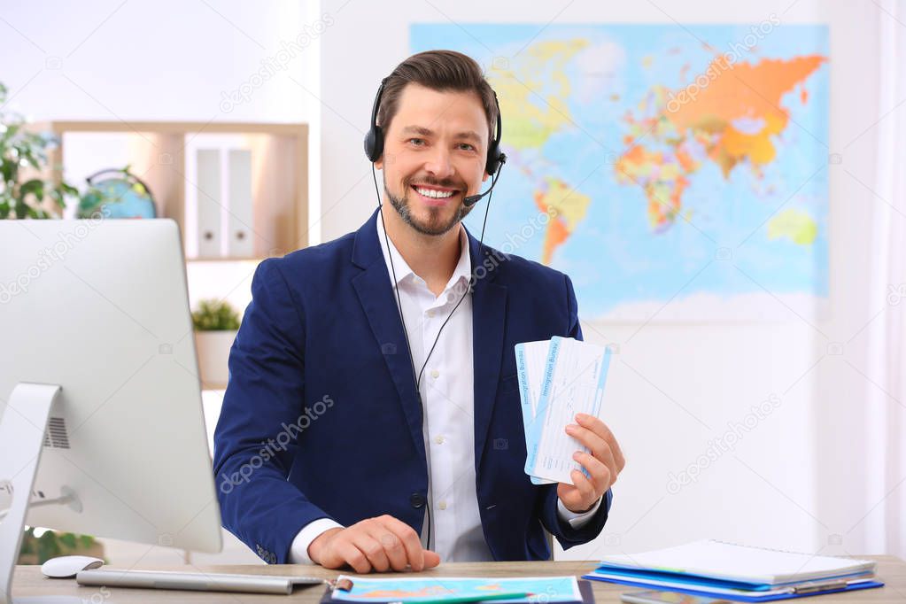 Male consultant with headset holding tickets in travel agency