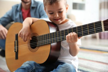 Baba oğlu evde gitar çalmak izlerken