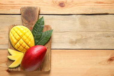 Kurul üzerinde ahşap arka plan, üstten görünüm taze mango meyve ile. Metin için yer