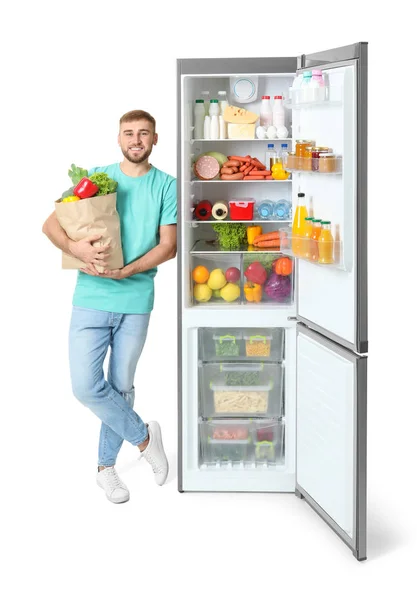 Ung Mann Med Pose Med Dagligvarer Nær Åpent Kjøleskap Hvit – stockfoto