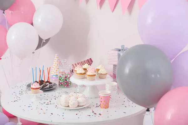 Party treats and items on table in room decorated with balloons