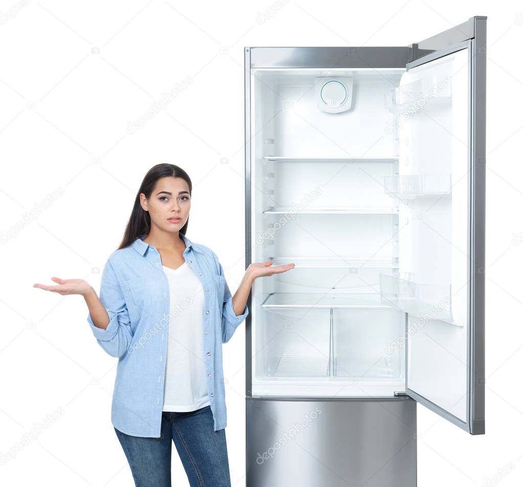 Emotional woman near empty refrigerator on white background