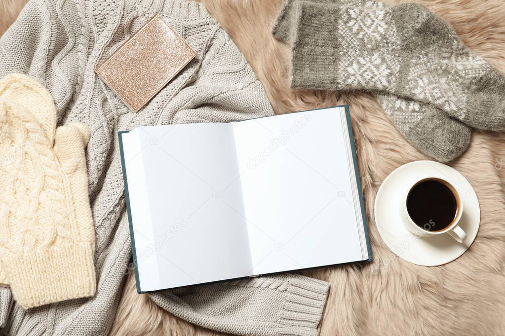 Flat lay composition with book, cup of coffee and warm clothes on fuzzy rug. Space for text