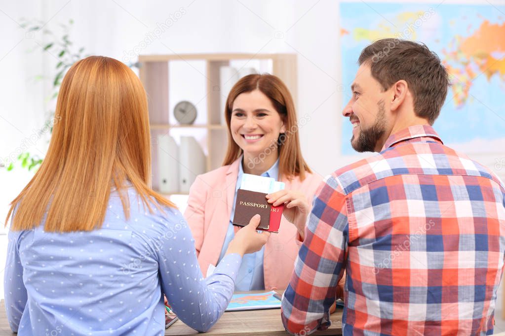 Female manager giving passports with tickets to couple in travel agency