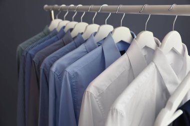 Wardrobe rack with men's clothes on grey background, closeup clipart
