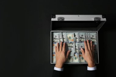 İşadamı ile koyu arka plan, üstten görünüm para dolu çanta