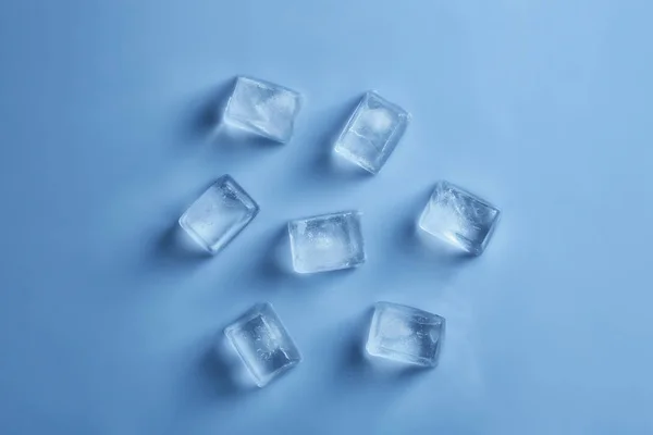 Ice cubes on color background, top view