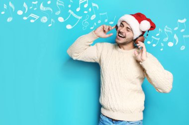 Noel Baba şapkası müzik notlar mavi arka plan, metin için yer ve kulaklık ile genç adam. Noel ve yeni yıl kutlama