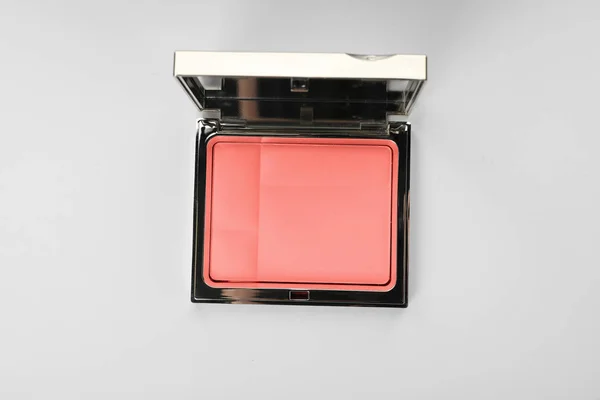 Powder blusher with mirror on light background, top view. Living coral color