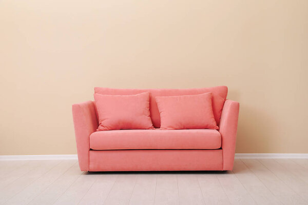 Stylish sofa near wall. Interior design with living coral color 