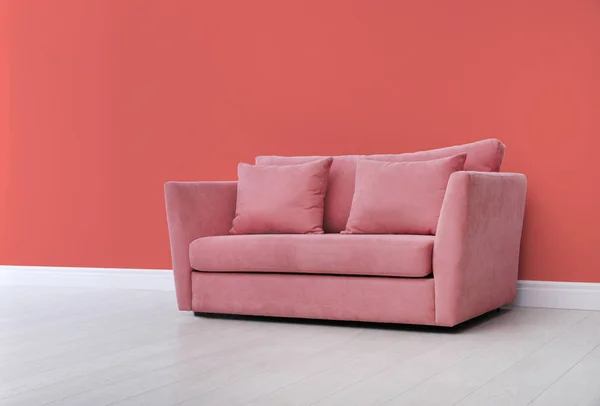 Stylish sofa near wall. Interior design with living coral color
