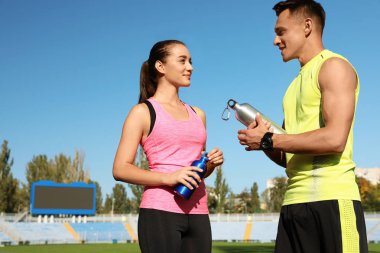 Genç sportif holding şişe su Stadyumu'nda güneşli günde çift.