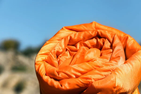 Orange sleeping bag on blurred background. Camping equipment
