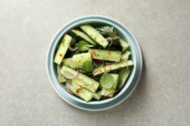 Lezzetli salatalık salatası soğan ve gri arka plan, üstten görünüm üzerinde kase ıspanak