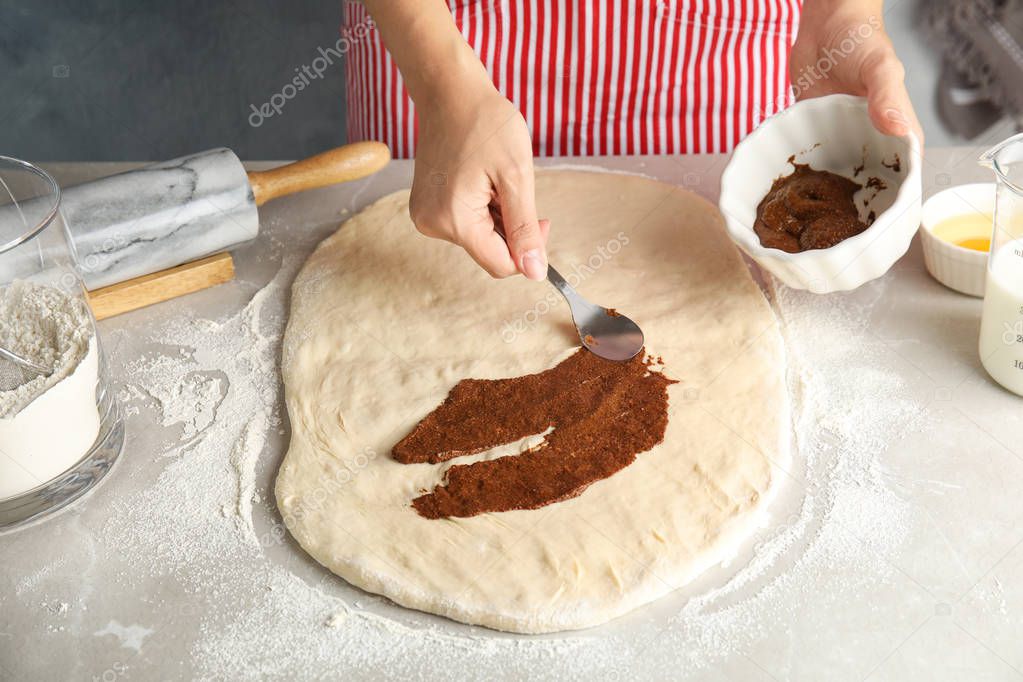 Woman making cinnamon rolls at table, closeup