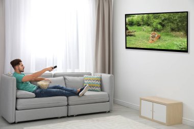 TV izlerken, evde kanepenin üzerinde patlamış mısır yemek genç adam