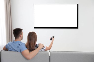 Evde kanepede televizyon izlerken bir çift. Mockup tasarım için