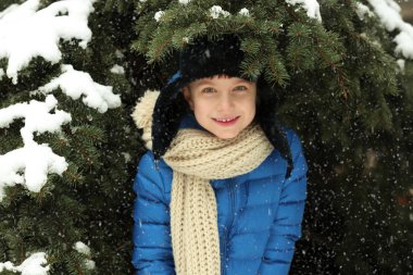 Küçük çocuk ağaç dalları altında açık havada karlı gününde gizleme