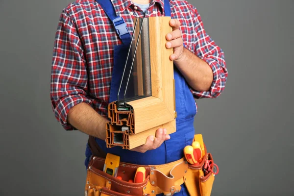 Installation worker with sample of modern window profile on gray background