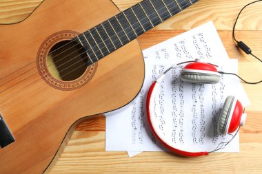 Güzel klasik gitar, kulaklık ve müzik levhalar üzerinde ahşap arka plan, üstten görünüm