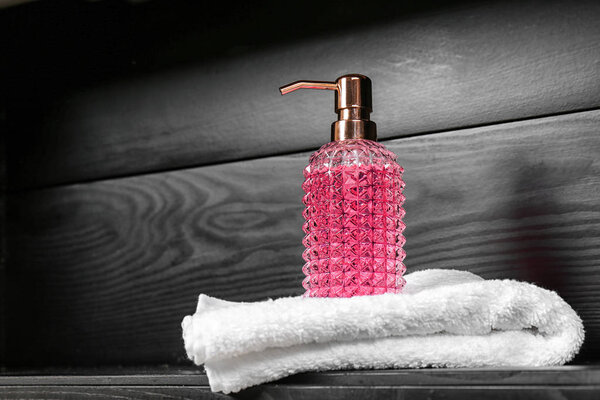 Glass soap dispenser and towel on table. Space for text