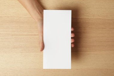 Boş broşürü ahşap masa, üstten görünüm kadar sahte tutan kadın