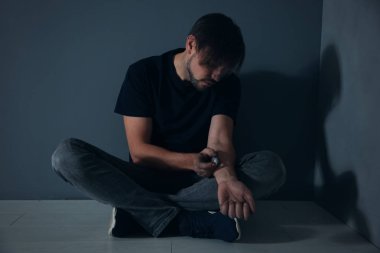 Erkek uyuşturucu bağımlısı gri duvara verme enjeksiyon