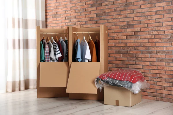 Wardrobe boxes with clothes against brick wall indoors