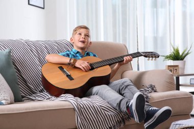 Sevimli küçük çocuk odasında kanepede gitar çalmak