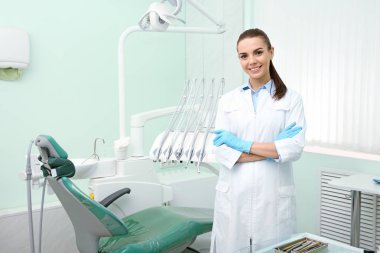 Young female dentist in white coat at workplace. Space for text clipart