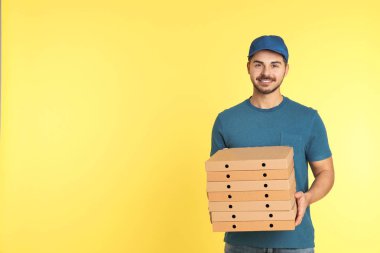 Genç kurye ile pizza kutuları üzerinde renk arka plan, metin için yer. Gıda dağıtım hizmeti