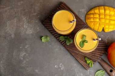 Gözlük taze mango içecek ve meyve masada. Metin için yer