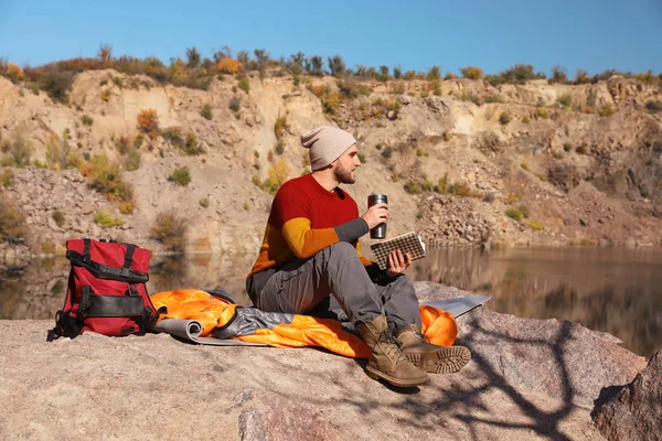 Camper Maschio Con Thermos Libro Lettura Mentre Seduto Sul Sacco — Foto Stock