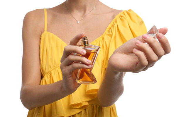 Young woman spraying perfume onto skin against white background, closeup