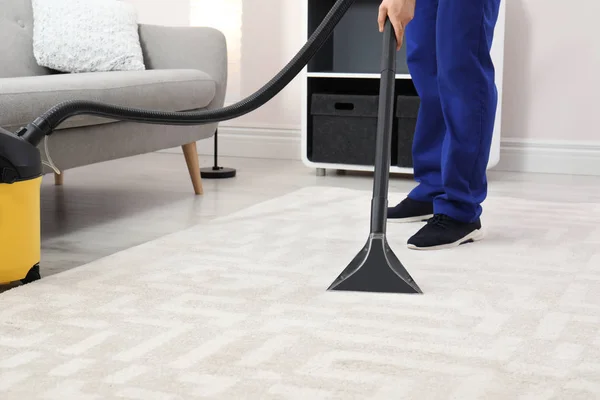 Man removing dirt from carpet with vacuum cleaner indoors, closeup. Space for text