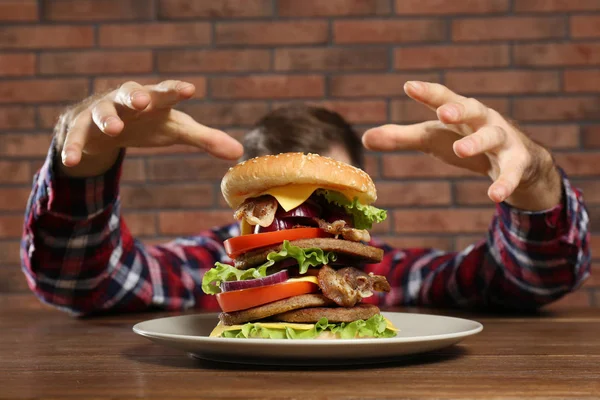 饥饿的人和桌子上的巨大汉堡 — 图库照片