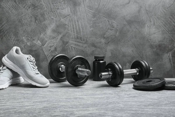 Composition with dumbbells and fitness accessories on floor. Space for text