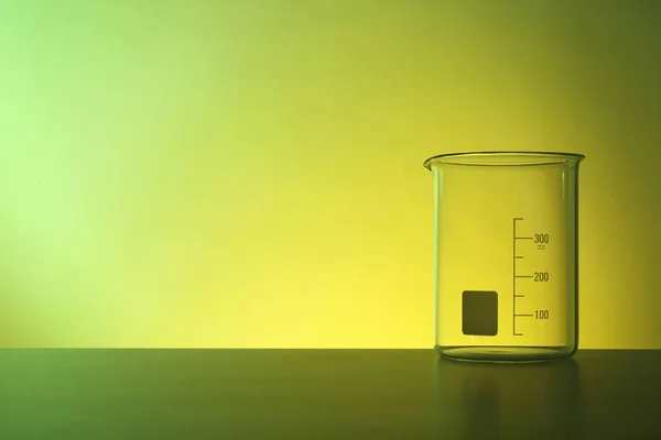 针对颜色背景的桌子上的空烧杯 化学实验室玻璃器皿 — 图库照片