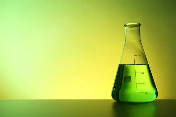 锥形烧瓶与液体在桌子上反对颜色背景 化学实验室玻璃器皿 — 图库照片