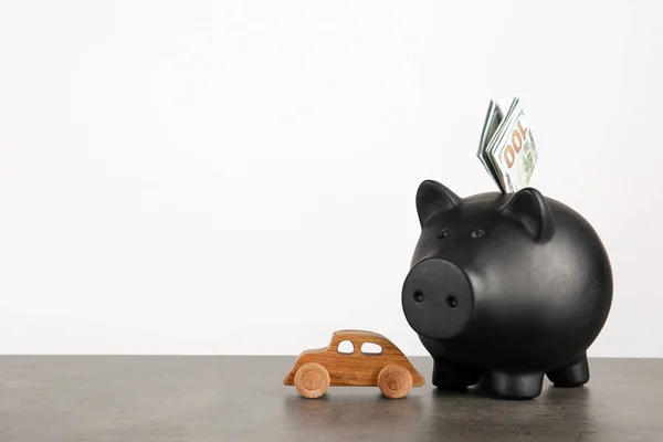 Piggy bank with dollar banknotes and toy car on table against white background. Space for text
