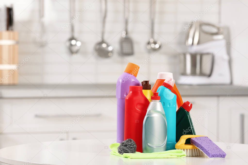 Set of cleaning supplies on table in kitchen. Space for text