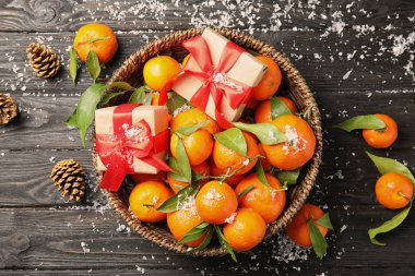 Christmas composition with ripe tangerines and gift boxes on wooden background, flat lay clipart