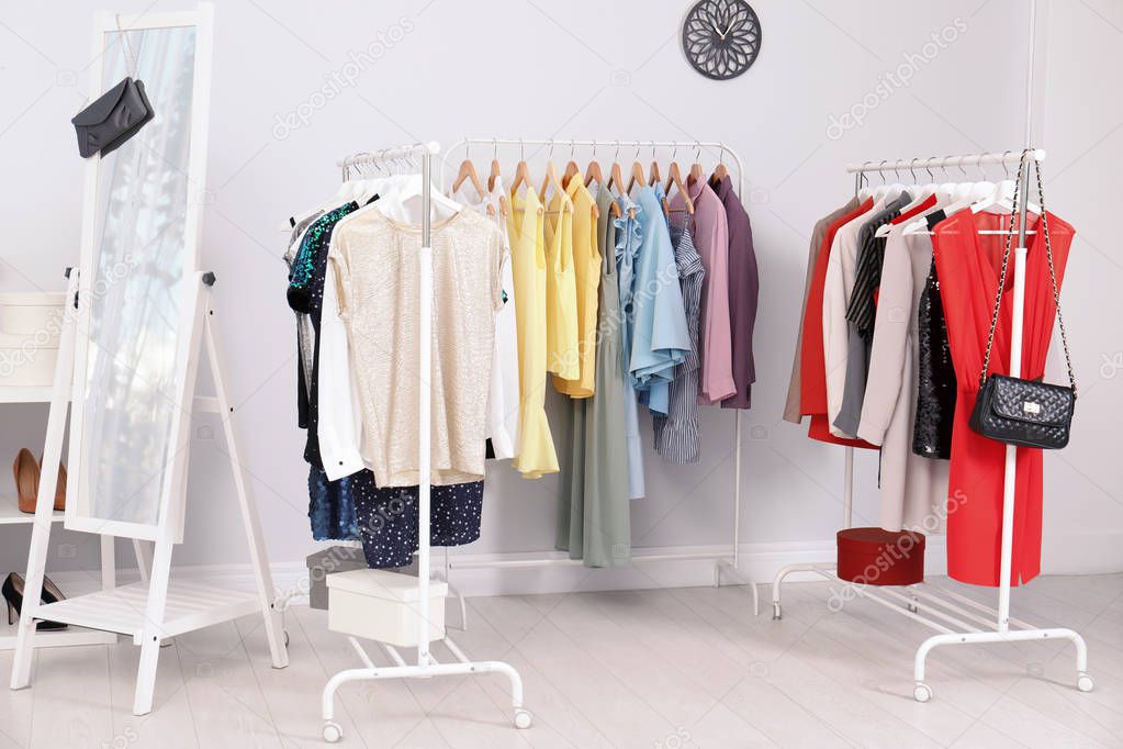 Wardrobe racks with different stylish clothes in light room