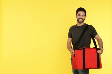 Renk arkaplanı termo çantalı genç kurye, mesaj için boşluk. Yemek dağıtım servisi.