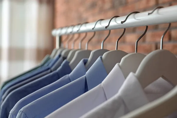 Wardrobe rack with men\'s clothes on hangers, closeup