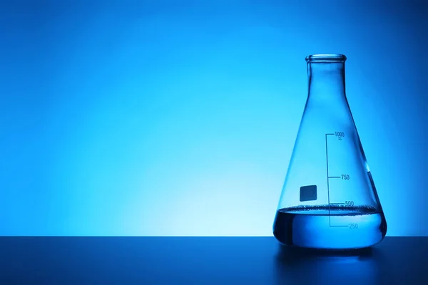 锥形烧瓶与液体在桌子上反对颜色背景 化学实验室玻璃器皿 — 图库照片