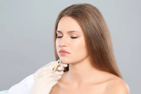 Jonge Vrouw Krijgen Lippen Injectie Grijze Achtergrond Cosmetische Chirurgie — Stockfoto