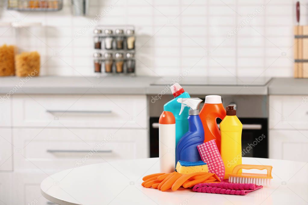 Set of cleaning supplies on table in kitchen. Space for text