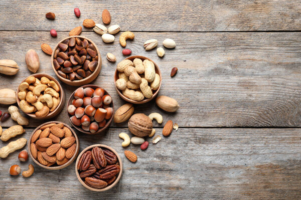 Плоская композиция с органическими орехами и пространством для текста на деревянном фоне, вид сверху. Снэк
