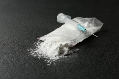 Plastik torba ve şırınga koyu arka plan üzerinde kokain